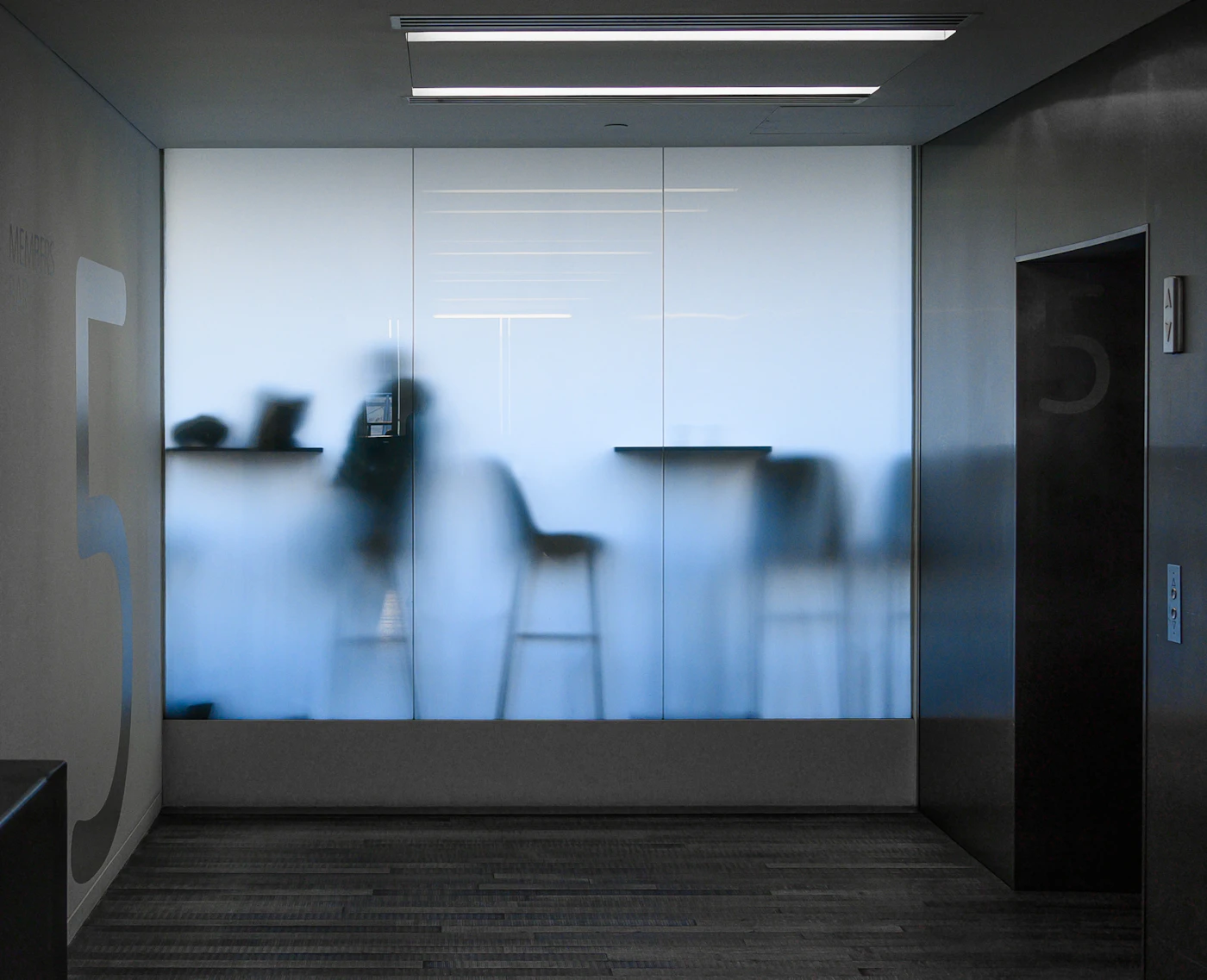 A frosted glass partition with the figures behind it softened to silhouettes